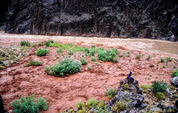 People standing on rocks overlooking the Colorado River during a large flash flood