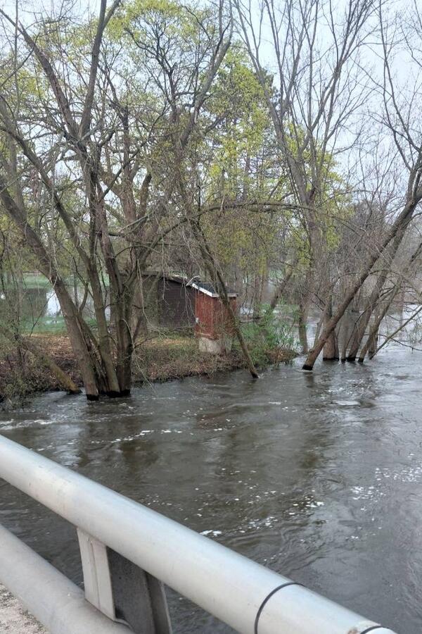 Red streamgage housing on banks of a flooded river