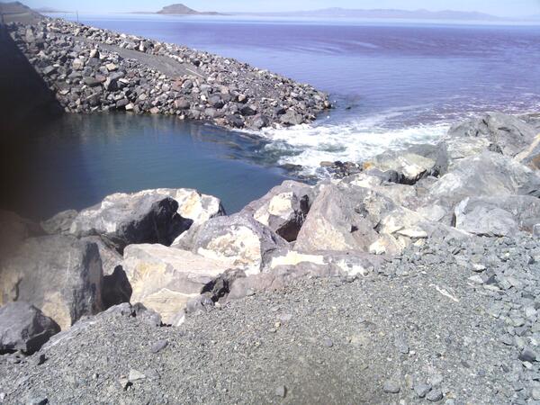 A rocky causeway divides the waters of the Great Salt Lake, with distinct color variations visible between the north and sout