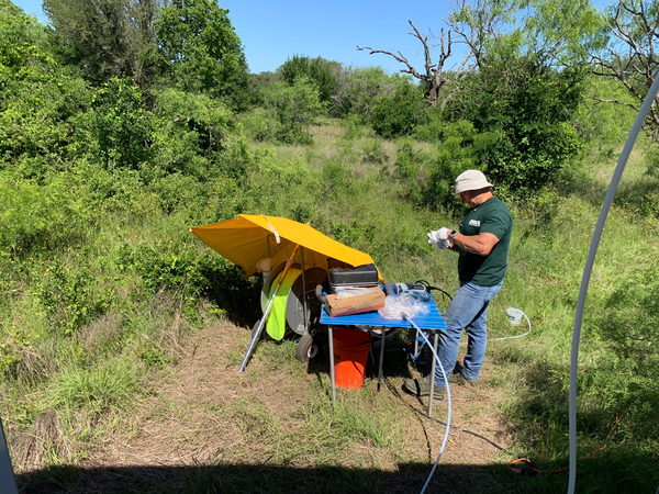 Image of man with water sample near a mobile lab in a open forest