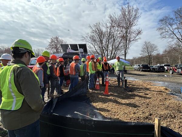 Alton Anderson of the USGS explaining common geophysical tools used to evaluate boreholes to a group of people at a worksite.