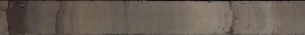 Photo of a one meter long cross-section of a sediment core with alternating layers of shades of greys and browns