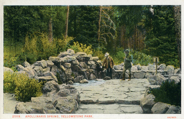 Colored 1920s postcard with two people on a stone platform hosting a cold water spring within a forested area