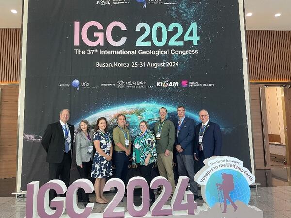 U.S. delegates stand with the International Geological Congress 2024 banner and sign