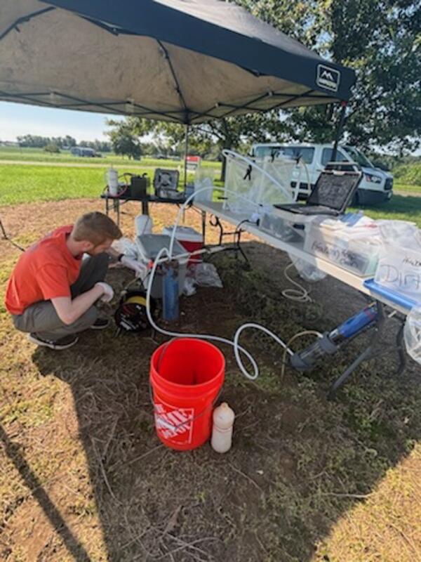 Scientist setting up sampling pump in well pipe.