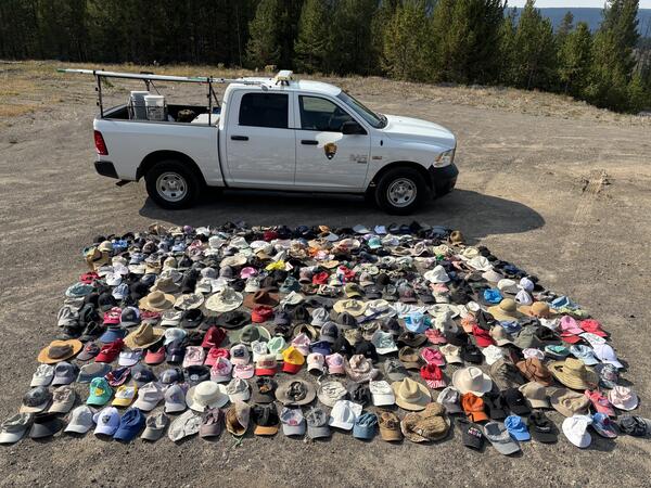 Hundreds of hats laid out for display with a truck in the background providing a sense of scale