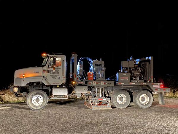 Truck parked in front of Continental Divide sign in Yellowstone National Park at night. Sign is illuminated by headlights.