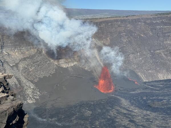 Color photograph of vent erupting on side of crater