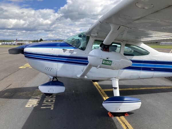 a small white aircraft with a blue, white, and black stripes running down the middle and plane nose.