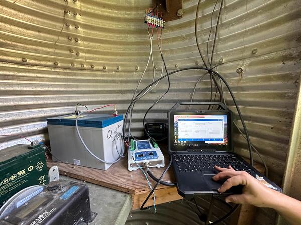 Inside of a monitoring site. Various equipment and a laptop are hooked up to a battery power supply.