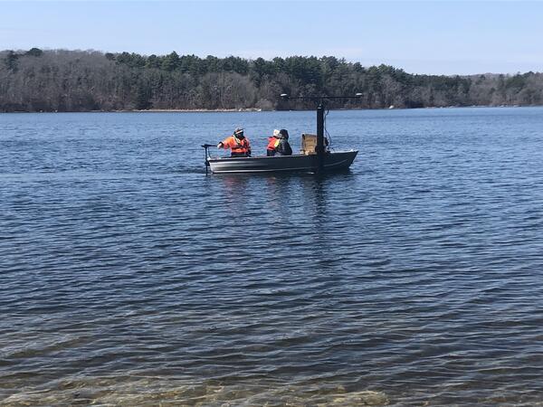 small boat on pond with trees in the background