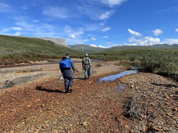 Two people walking up an orange creek bed.