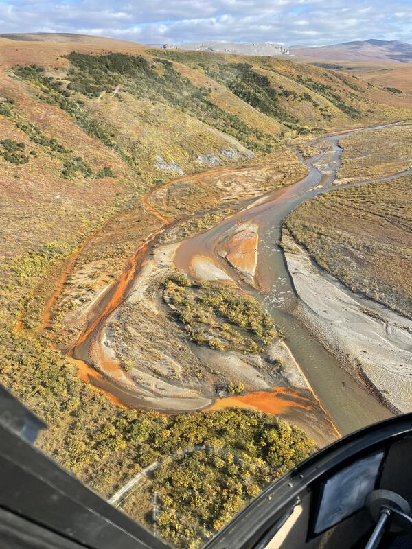 An orange stream flowing into a larger blue river.