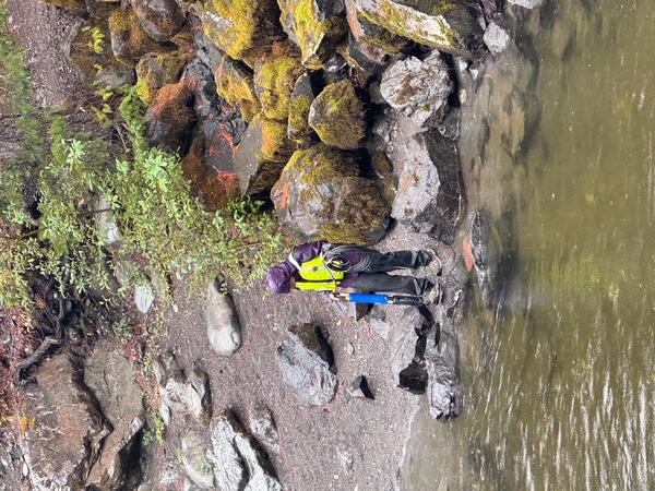 Scientist carries measuring device near river