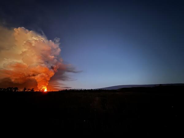 Color photograph of eruptive plume and mountain in sunrise