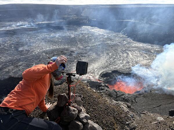 Color photograph of scientist checking a webcamera monitoring an eruption