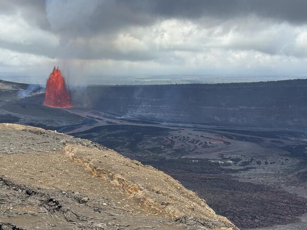 Color photograph of lava fountain with crater rim in foreground