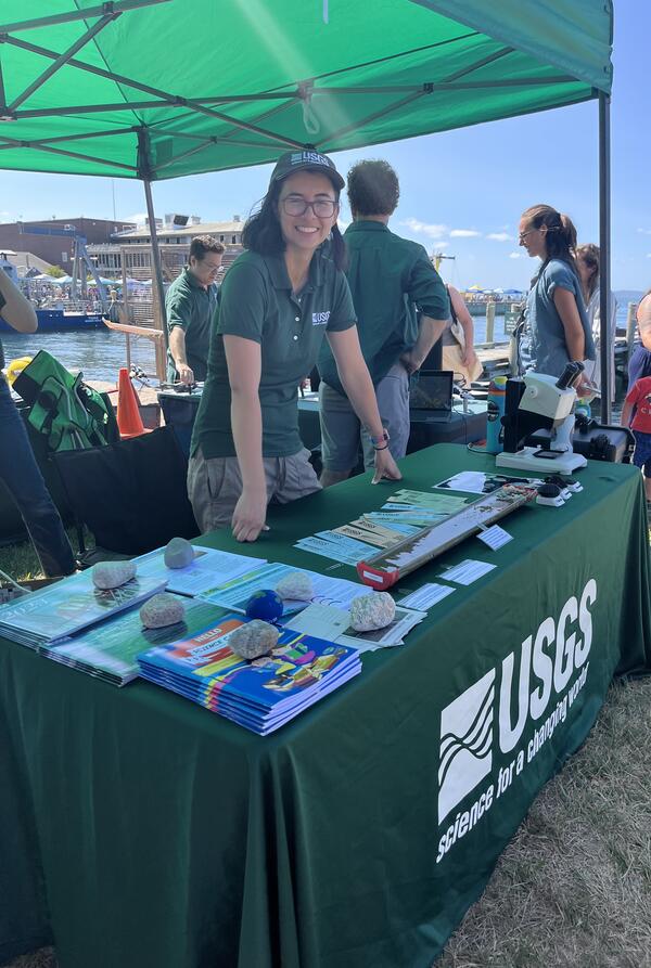 person standing behind USGS booth outside under tent