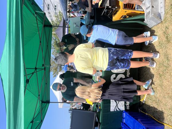 three kids visiting the USGS booth under a tent outside