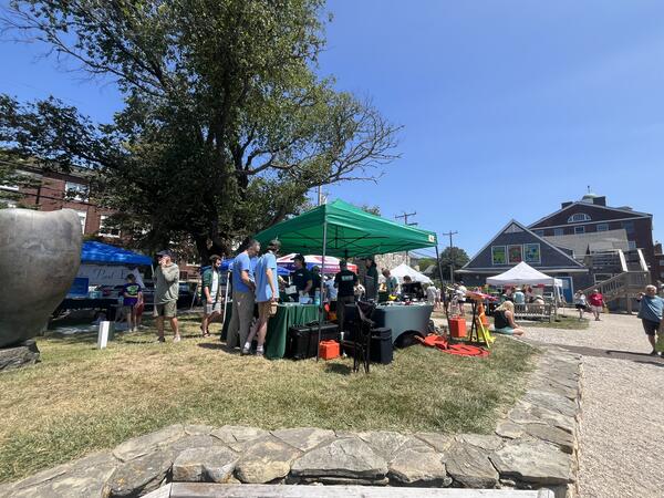 USGS tent and four tables with people visiting the booths to talk to the scientists