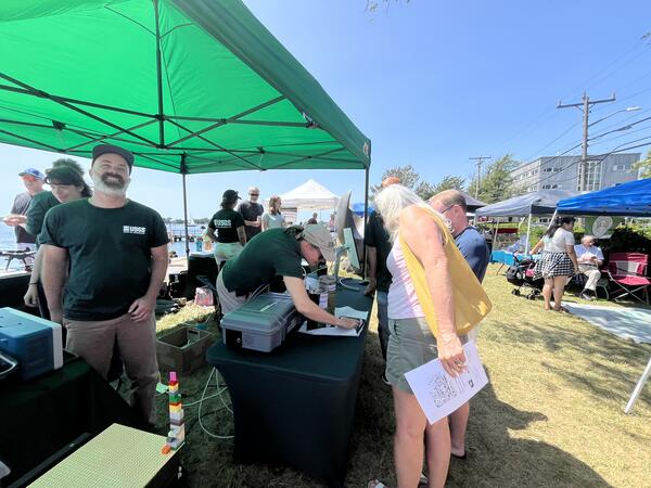 USGS scientists talking to visitors at booth under tent outside