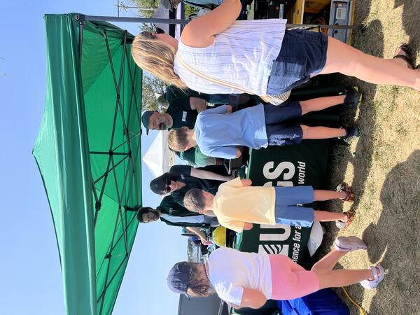 people visiting USGS booth outside under tent
