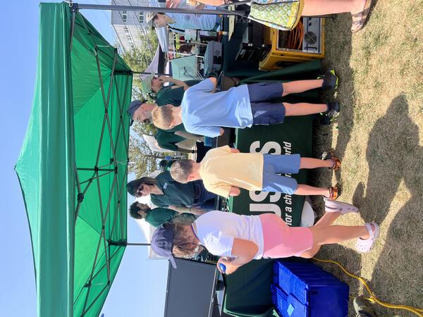 USGS scientists standing behind booth while kids play with Legos on the table