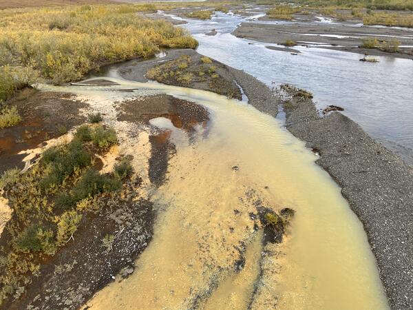 Pale orange river entering clear blue river.