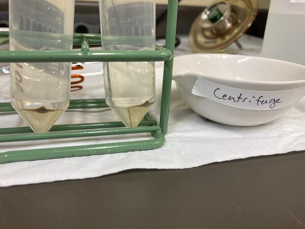 Test tubes sit in rack next to crucible labeled "Centrifuge"