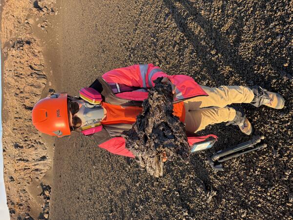 Color photograph of scientist holding lava bomb