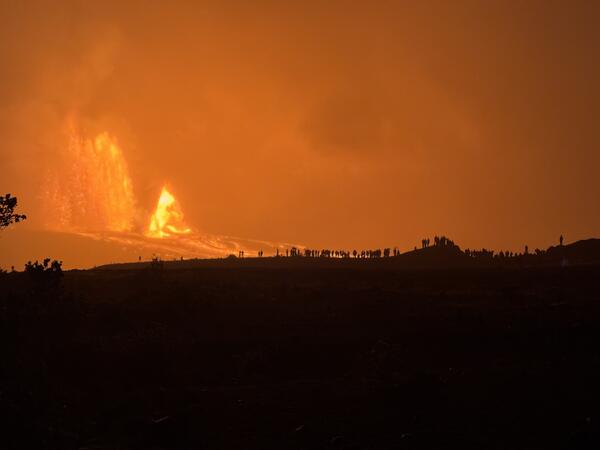 Color photograph of lava fountain with people silhouetted by the glow