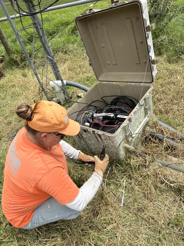 Color photograph of field engineer replacing wires at volcano monitoring station