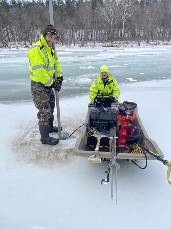 Scientists taking a reading of the flow under the ice on the river