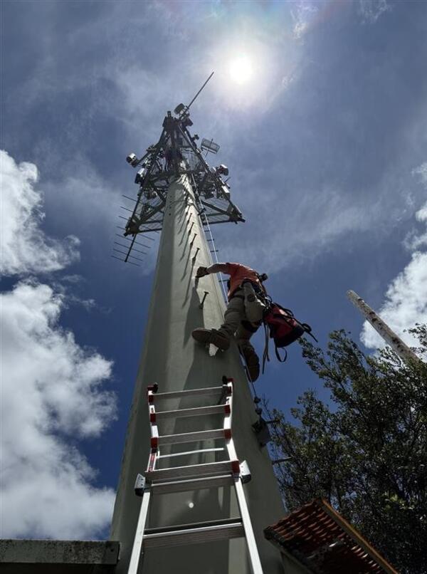Color photograph of field engineer climbing tower