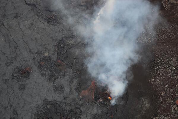 Color photograph of volcanic vent with lava visible within