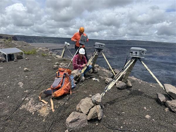 Color photograph of scientist installing webcameras on rim of volcano