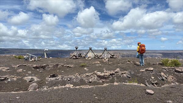 Color photograph of scientist near volcano monitoring equipment