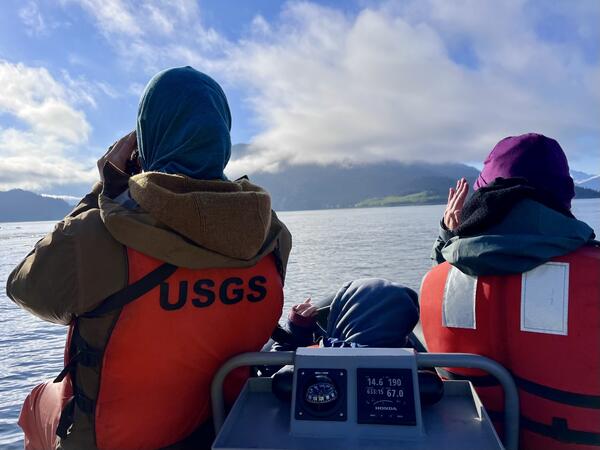 Two people wearing orange life jackets facing away from the camera.
