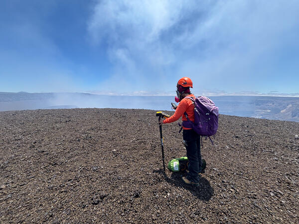 Color photograph of scientist measuring volcanic deposit
