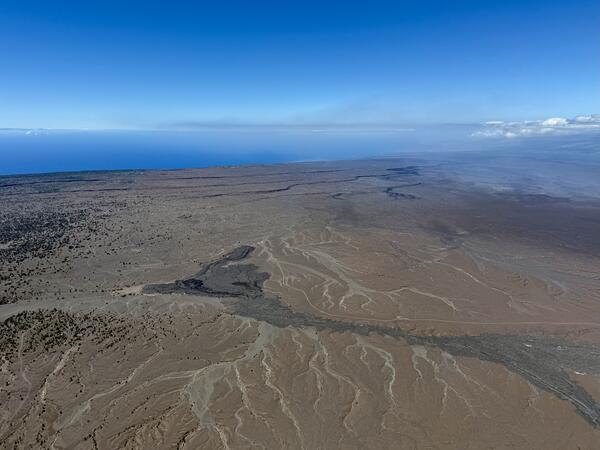 Color photograph of volcanic landscape and ocean in the distance