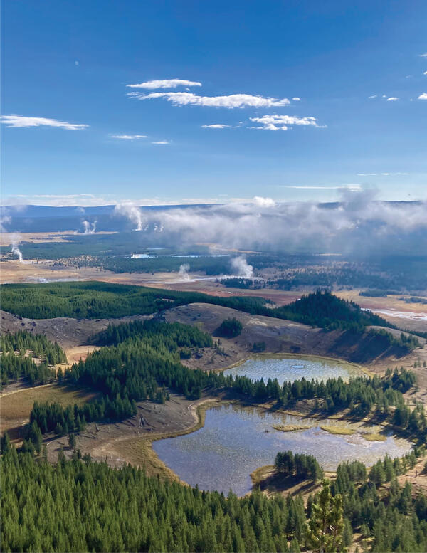 Small lakes occupy a landscape of forests and meadows under partly cloudy sky