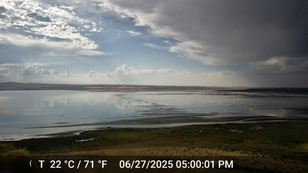 shallow lake water reflects a partly cloudy sky in the yellow landscape of the Oregon outback.