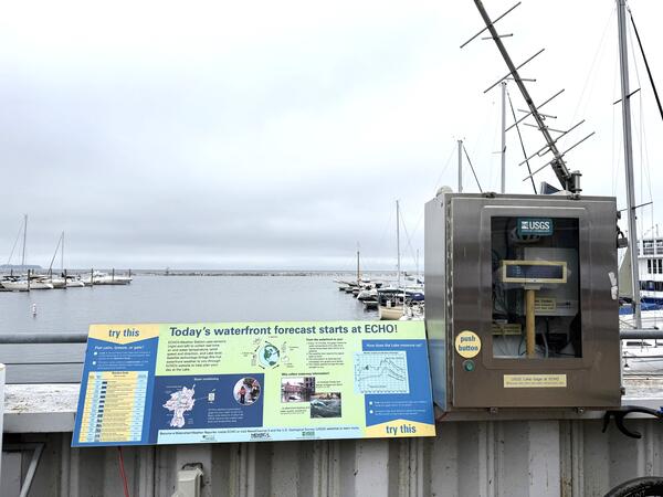 A streamgage next to a sign on the water.
