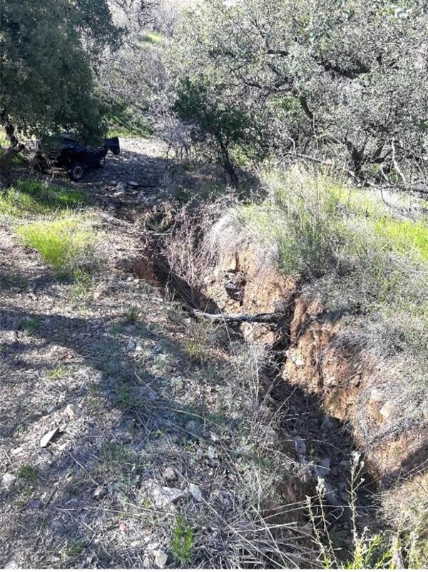 Figure 2. Photographs around the Santa Margarita Ranch including, a) USGS scientists investigating vertical-walled crack from degraded earthen berm; b) vibrant desert landscape featuring a "carpet" of golden Mexican Gold Poppies and purple Coulter's Lupine blooming among rocky soil and sparse vegetation; c) incising narrow, eroded gully or wash cutting through a dry, hilly landscape, and; d) desert arroyo (also known as a dry wash), characterized by a deep, eroded gully carved into the sandy, arid soil, wit