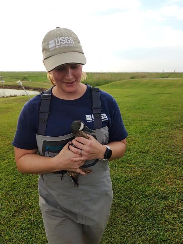 Woman wearing cap and waders, holding a duck