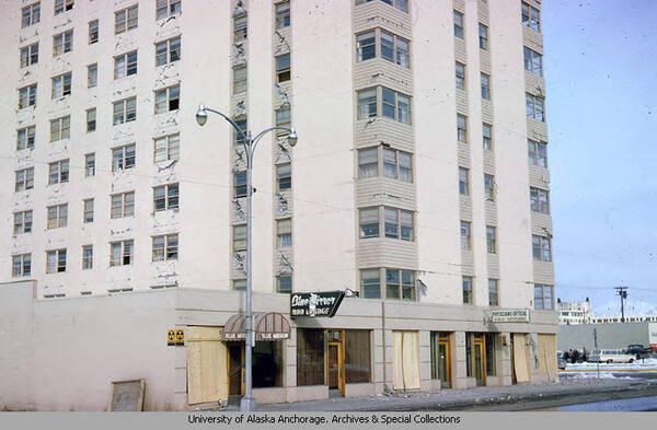 Cracks in multiple story building. Streetlight in front with wood panels converging broken glass doors and windows. 