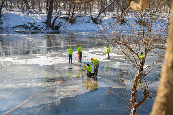 Six people standing on an iced over river.