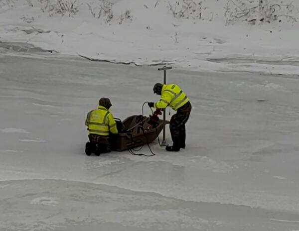 Two Scientists working off of a sled on a frozen river 