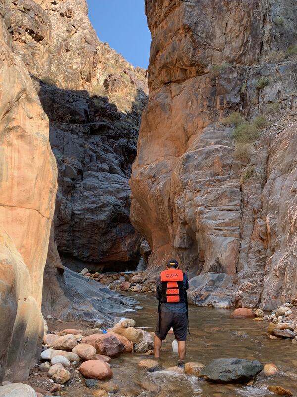Nick Paretti, wearing a red life jacket, measures water flow in a Grand Canyon tributary