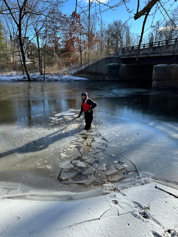 Scientist breaking up and wading through ice covered river